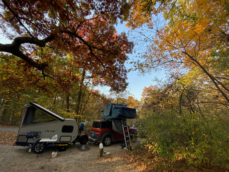 Autumn camping with an RV rental! A pop-up camper & SUV with roof-top tent are set amidst vibrant fall foliage.