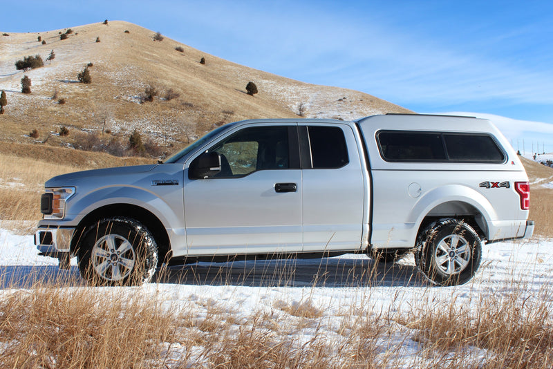 an ideal **rv rental** for mountain camping adventures.|A silver Ford F-150 4x4 pickup with a camper shell (like an RV rental) parked on snowy grass with a hill behind.|Spacious Ford F-150 crew cab interior — photo 18