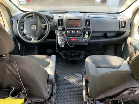 Spacious RV rental front cabin showcasing the steering wheel, detailed dashboard, and two dark gray front seats.