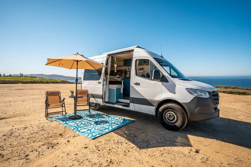  and a cozy bed area.|RV rental's compact kitchen with blue cabinets — photo 5