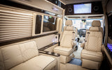 Experience luxury with this spacious van interior, ideal for an RV rental, featuring plush cream seating, a large screen, and elegant lighting.