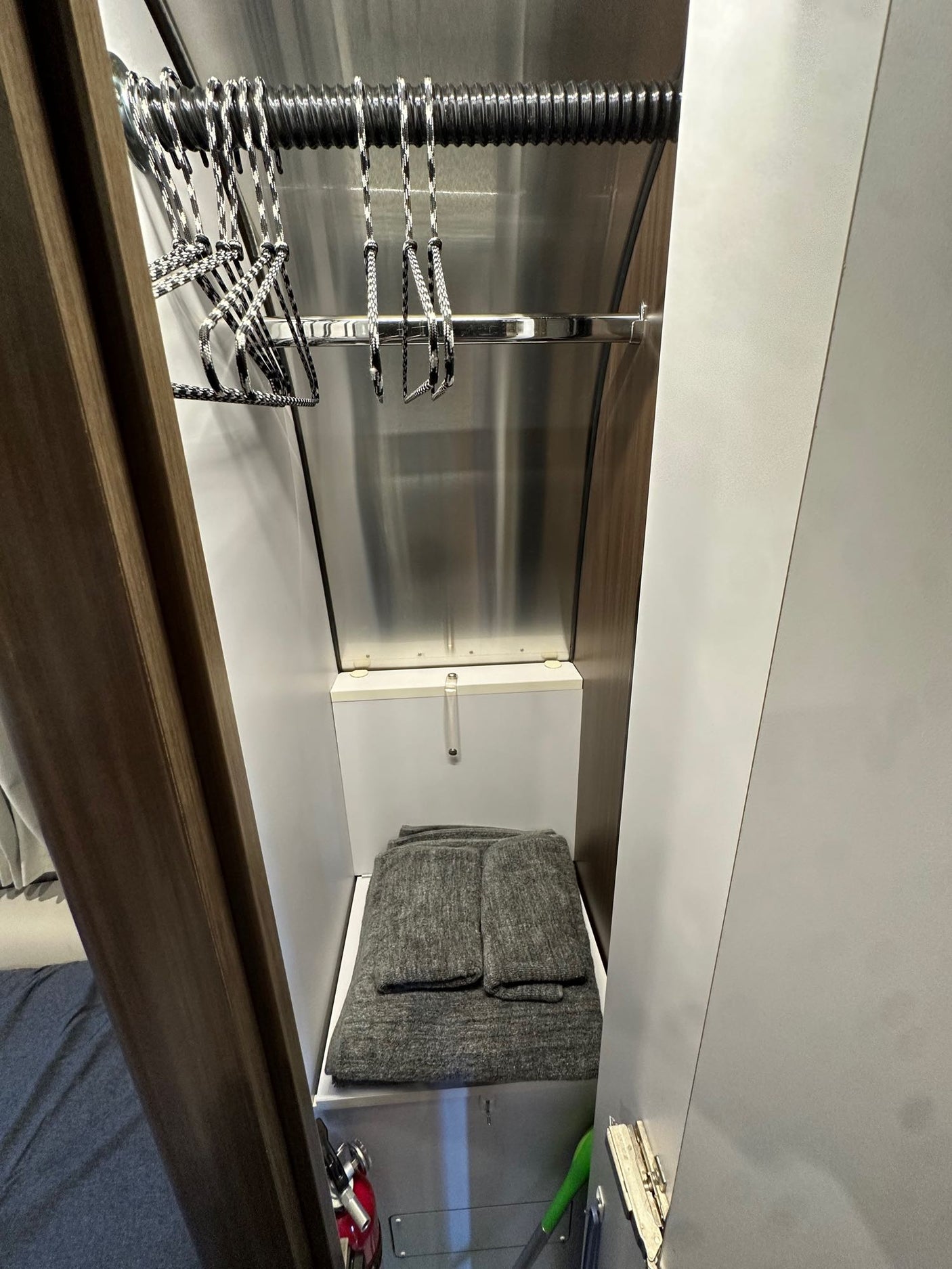 Inside an RV rental's compact wardrobe: hangers, folded blankets, and travel essentials for organized trips.