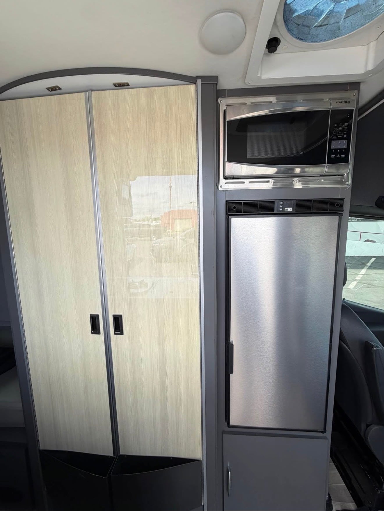 RV rental interior featuring a light wood closet, a built-in microwave, and a stainless steel refrigerator.