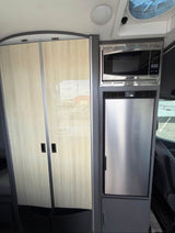RV rental interior featuring a light wood closet, a built-in microwave, and a stainless steel refrigerator.