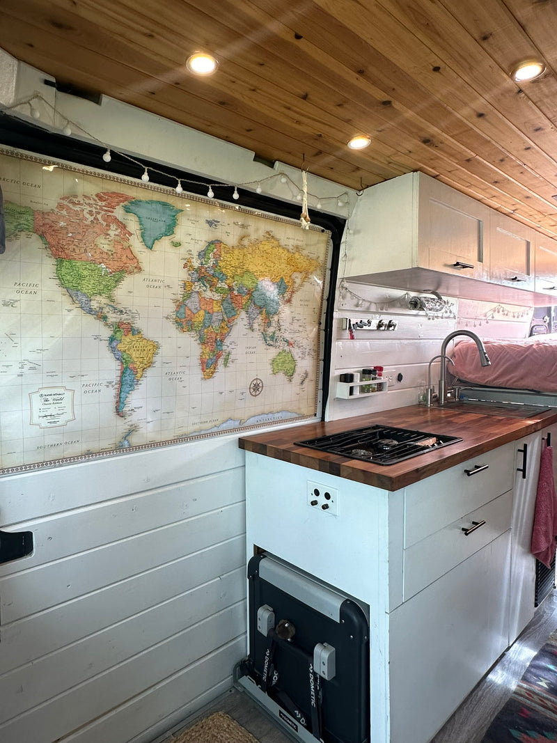 Modern rv rental camper van kitchen with wooden ceiling, world map, built-in stove & sink, plus a Dometic fridge. — photo 9