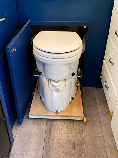 This RV rental features a pull-out composting toilet in a blue cabinet, optimizing space for comfortable mobile living.