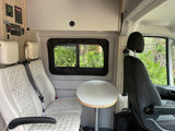 Experience comfort in this RV rental camper van interior. Features include plush seats, a table, and accessible control panels.
