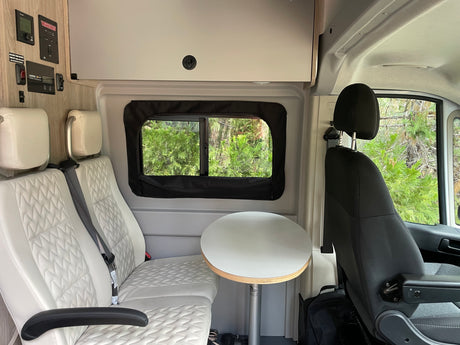 Experience comfort in this RV rental camper van interior. Features include plush seats, a table, and accessible control panels.