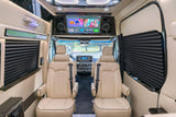 Plush rv rental interior with cream diamond-stitched captain's chairs, overhead screen with Netflix, & dark privacy blinds.