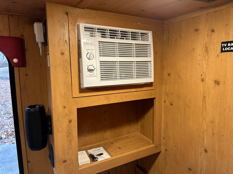 RV rental interior: A 'Perfect Aire' air conditioning unit is mounted in wood paneling, with built-in shelves and a charging station below. — photo 7