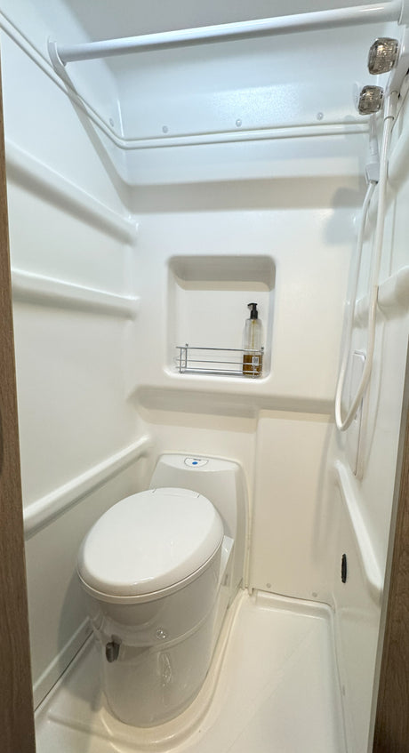 Practical RV rental wet bath: integrated toilet, shower, and built-in shelf for compact comfort.