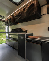 Sleek RV rental van interior: custom kitchen, fridge, and clever overhead storage for efficient travel setups.