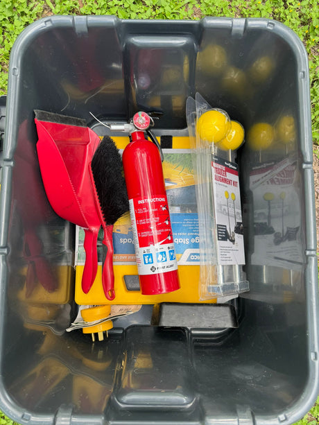 For your RV rental trip: A red fire extinguisher, dustpan, leveling pads, and trailer alignment kit packed in a bin.