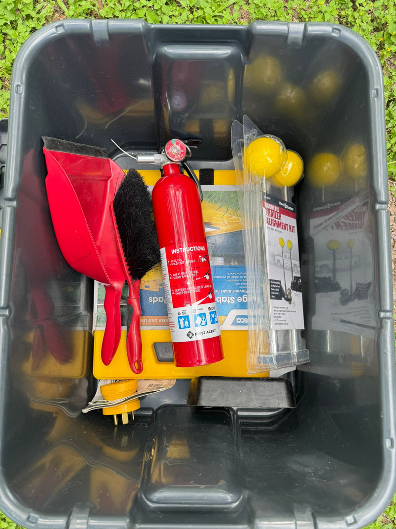 For your RV rental trip: A red fire extinguisher, dustpan, leveling pads, and trailer alignment kit packed in a bin. — photo 7