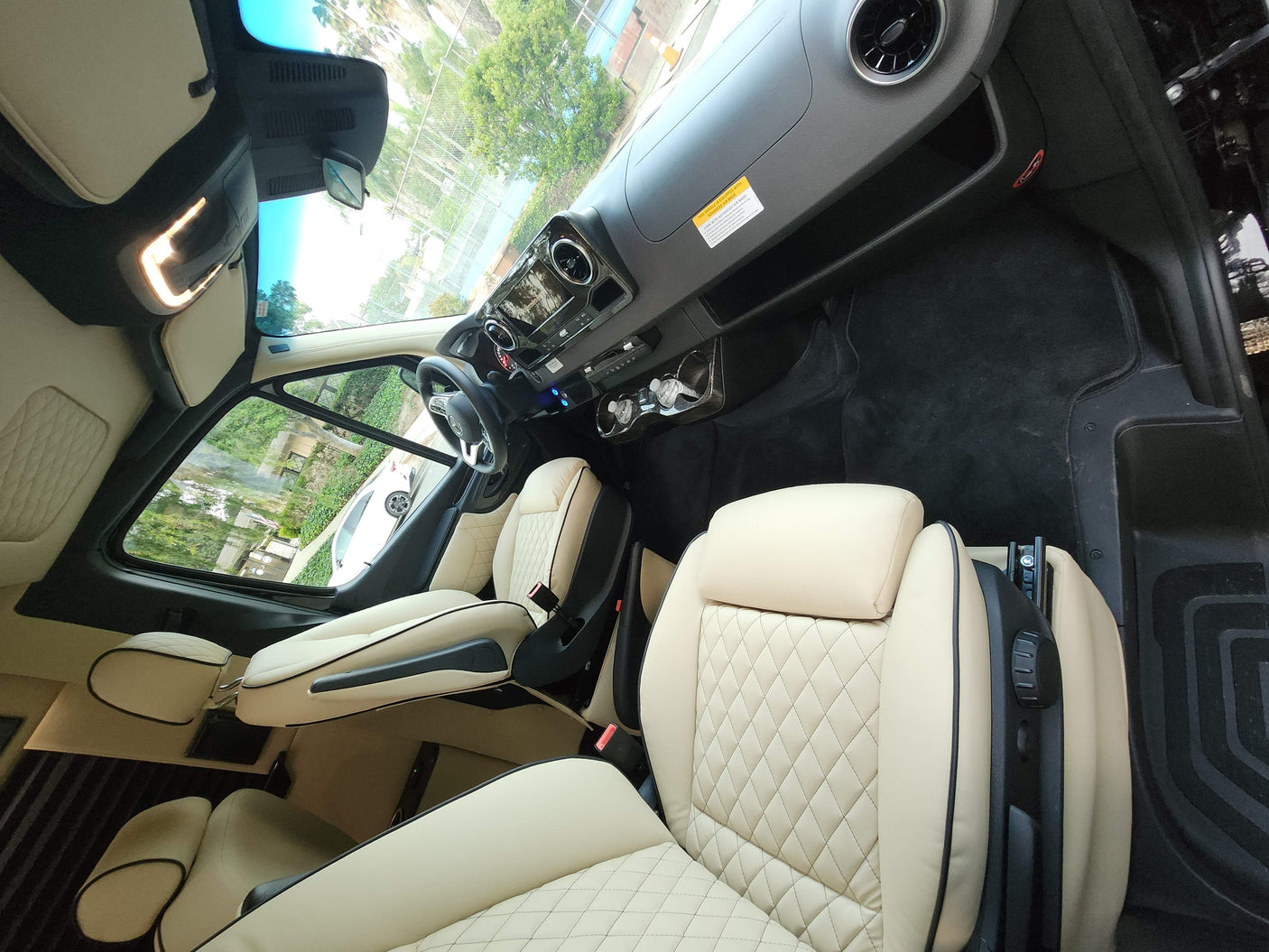 Modern RV rental interior featuring spacious, cream quilted leather seats and a Mercedes-Benz dashboard.