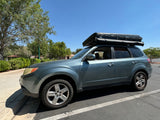 Green Subaru Forester SUV with a hardshell rooftop tent, ideal for RV rental camping adventures.
