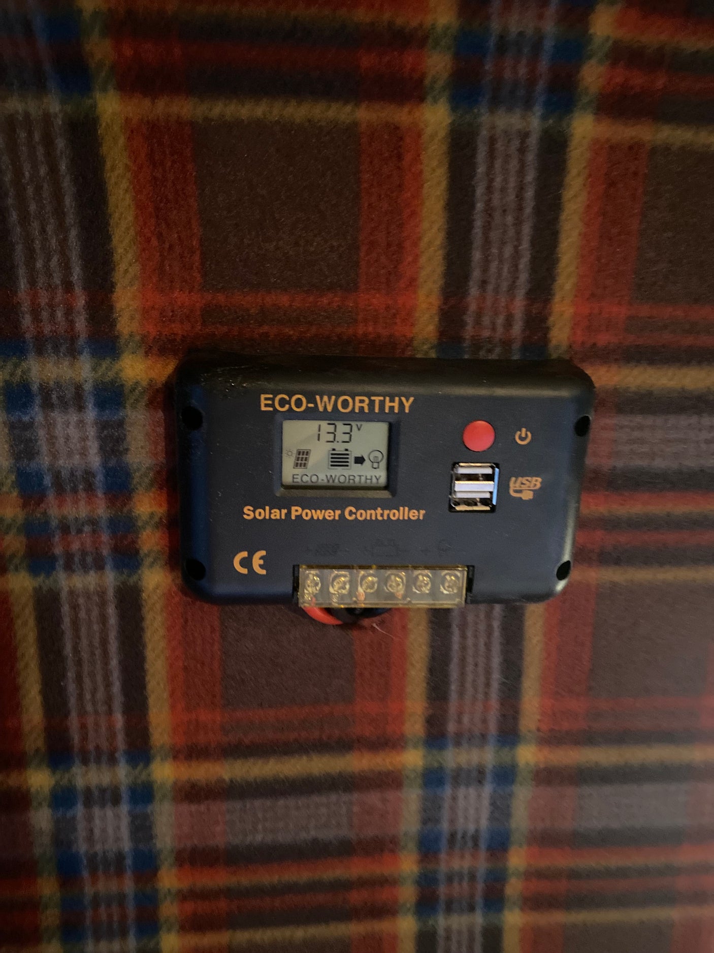 ECO-WORTHY Solar Power Controller showing 13.3V battery voltage. Located in an rv rental, it provides solar power management with USB ports.