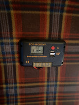 ECO-WORTHY Solar Power Controller showing 13.3V battery voltage. Located in an rv rental, it provides solar power management with USB ports.