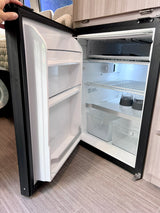 An open refrigerator inside an RV rental. Note the frosty freezer, shelves, bins, and cups, essential for your travels.