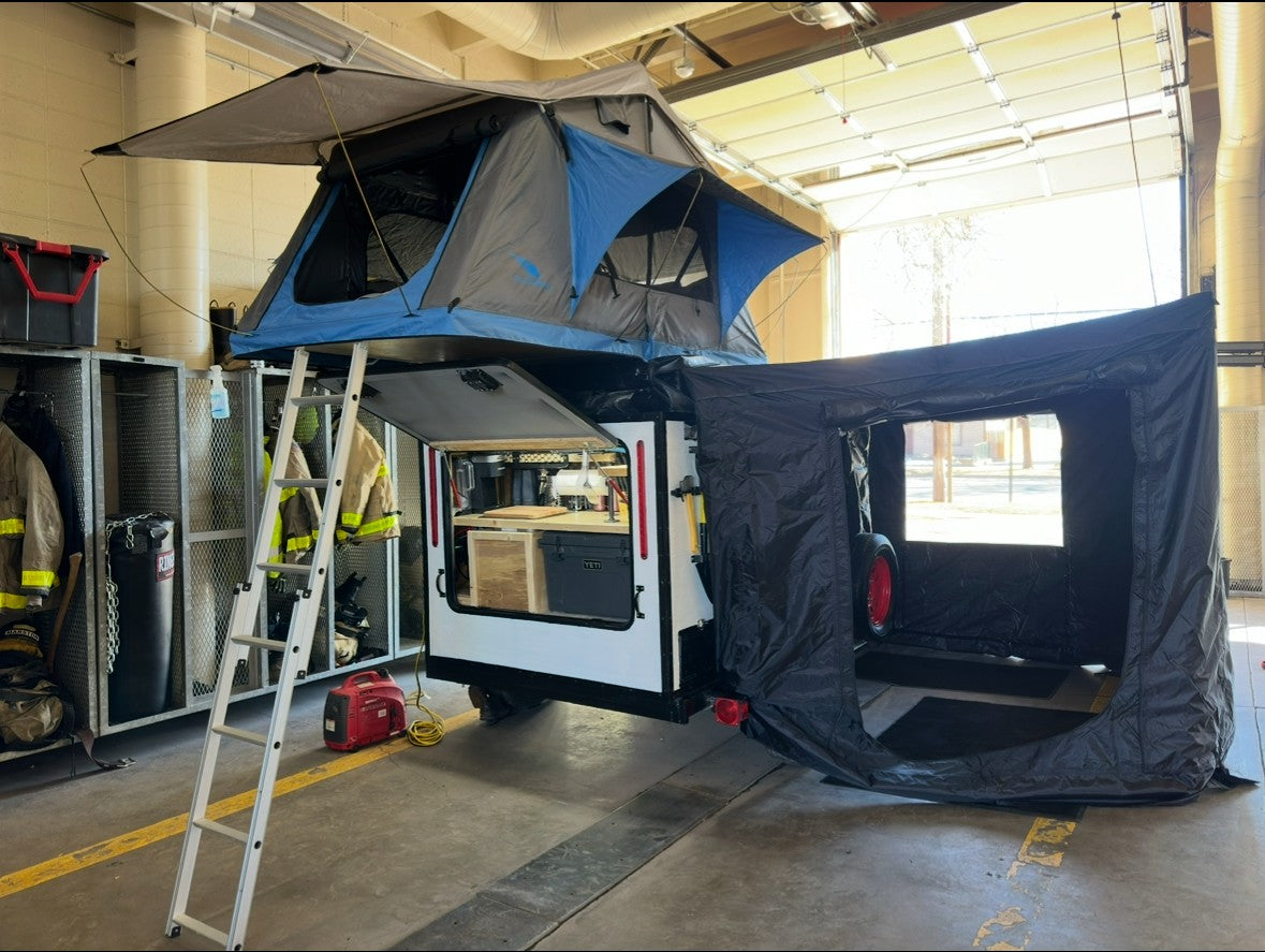 This RV rental setup features a camping trailer with a rooftop tent, annex, and portable kitchen, ready for adventure.