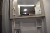 RV rental bathroom: A clean, compact space with a shower, mirror reflecting the RV interior, and light/fan controls.