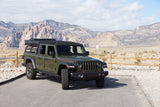 Green Jeep Gladiator with camping gear in desert mountains. An ideal RV rental for outdoor adventures.