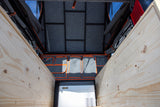 Optimized RV rental cargo space featuring wooden benches, a cooler, and hanging organizers. Ready for travel.