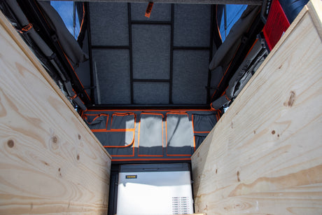 Optimized RV rental cargo space featuring wooden benches, a cooler, and hanging organizers. Ready for travel.