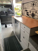 Inside this spacious rv rental, a compact kitchen with sink, fridge, storage drawers, and seating area awaits your journey.