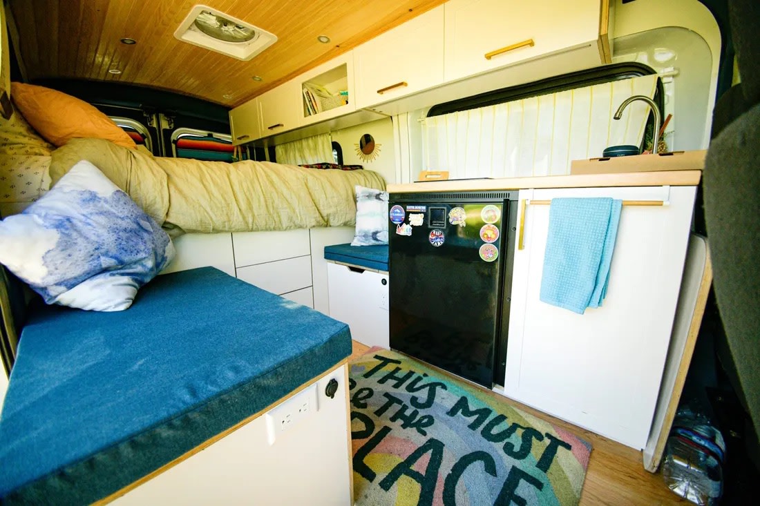  parked by a scenic mountain lake with snowy peaks.|Inside a cozy RV rental: a comfortable bed at the back — photo 3