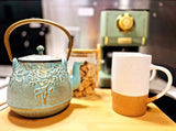 RV rental comfort: Teal cast iron teapot, two-toned mug & snacks ready for your journey.