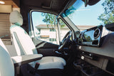 Luxury RV rental interior with bright driver's seat, Mercedes-Benz dashboard, and sunlit outdoor view.