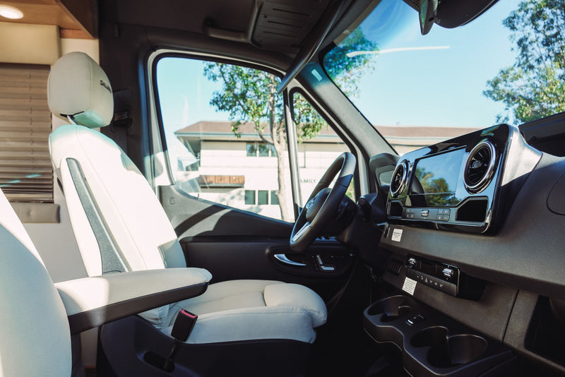 Luxury RV rental interior with bright driver's seat, Mercedes-Benz dashboard, and sunlit outdoor view. — photo 7