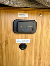 RV rental charging panel: USB-C PD/QC3.0 ports (blue light on) and LED strip light switch on wood.