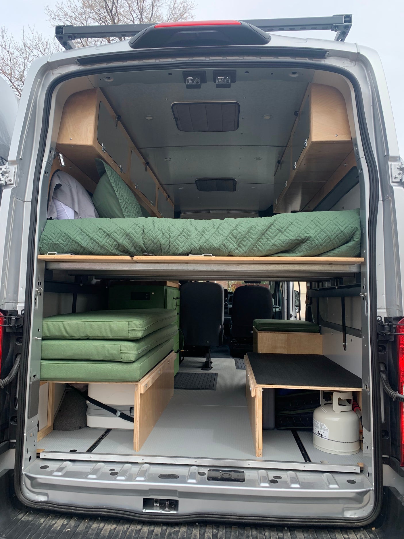 Inside an RV rental, a custom camper van layout features a convertible bed, integrated storage, and cooking essentials.