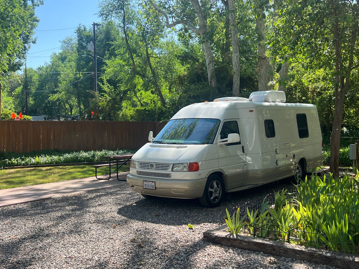 featuring a picnic area and utility hookups.|A cream Class B RV parked on a gravel campsite next to a picnic table — photo 4