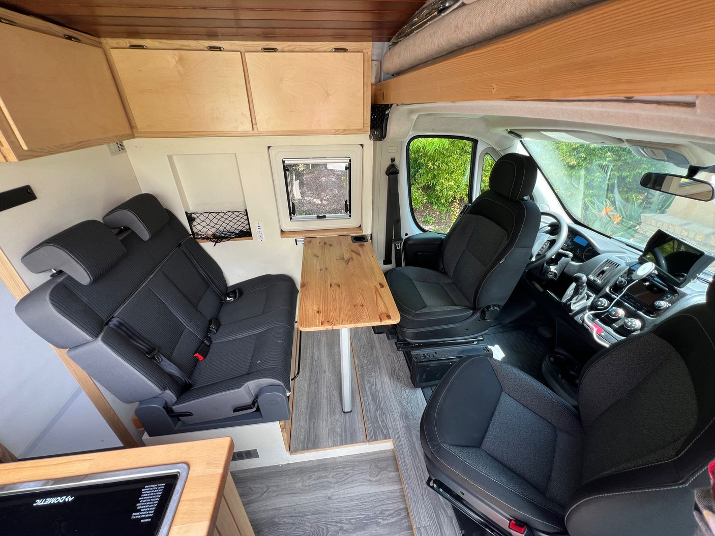 This rv rental's spacious interior features comfortable seating, a dining table, wooden cabinets, and front cabin.
