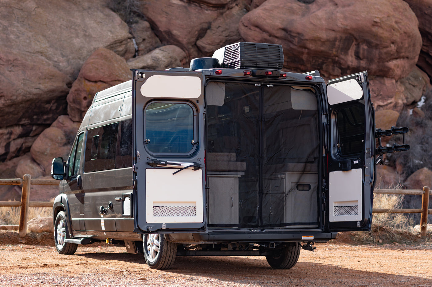 RV rental ready for adventure: Rear doors open on a sleek campervan, revealing its interior and bike rack setup.