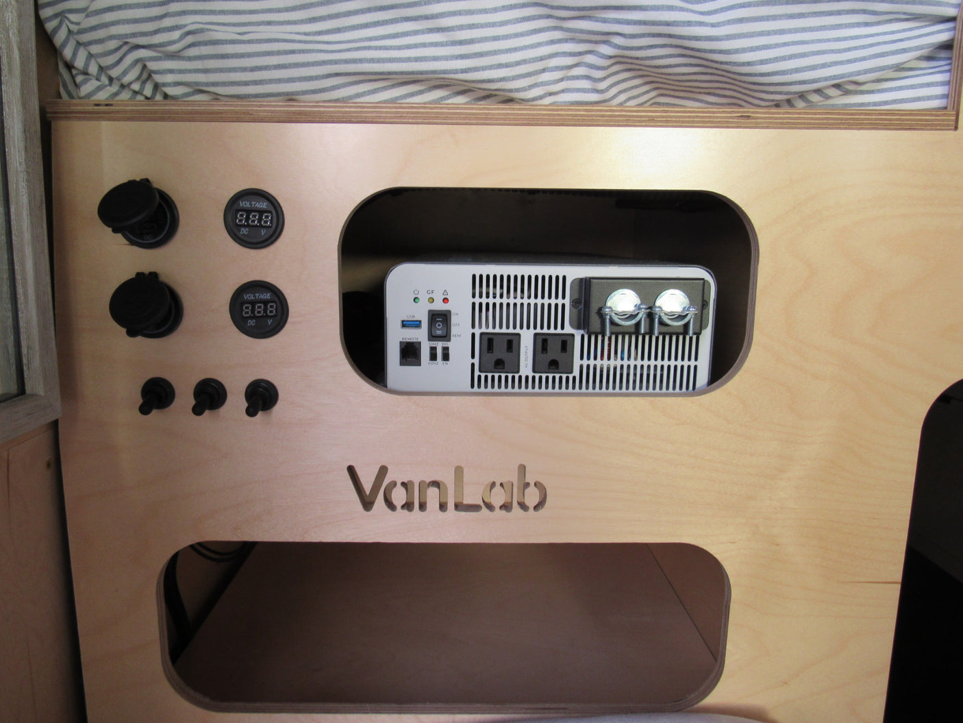 This RV rental features a VanLab power control panel: an inverter, USB & AC outlets, 12V sockets, and voltage displays for mobile power.
