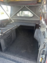RV rental featuring a custom truck bed with carpeted storage, built-in compartments, and a drawer system for adventure gear.