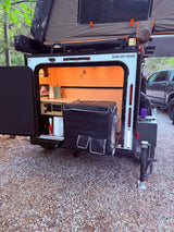 Zion Off-Road camper shows its open rear galley kitchen with fridge & controls, plus a rooftop tent. Great for an rv rental getaway.