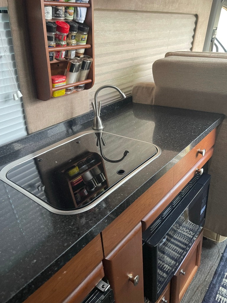  and overhead A/C unit with rugs.|RV rental kitchen: black countertop with sleek induction cooktop — photo 4