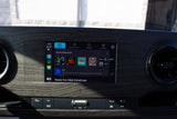 An RV rental's infotainment screen displays a personalized music player ("Made For Nick Einstman"), with physical media controls below.