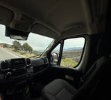 Scenic drive in an RV rental through a mountain landscape. Dashboard, steering wheel, and road ahead from driver's view.