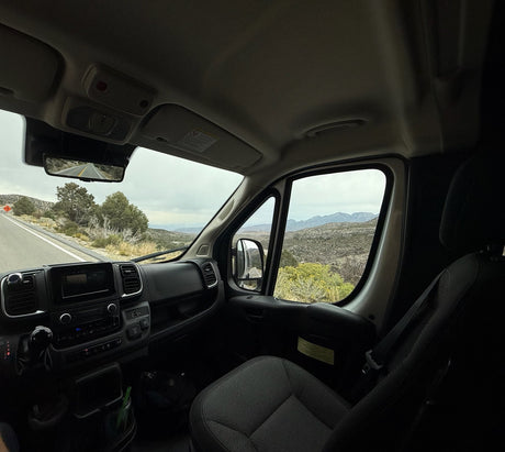 Scenic drive in an RV rental through a mountain landscape. Dashboard, steering wheel, and road ahead from driver's view.