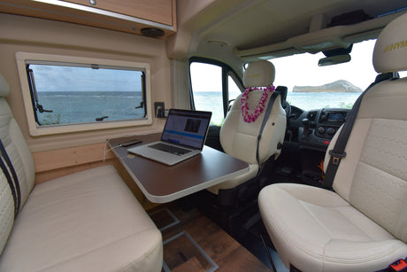 Remote work from your RV rental: a comfy interior with laptop, ocean, and island views, plus a welcoming lei.