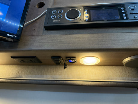 RV rental interior featuring a Roku TV, Jensen stereo, AC/USB outlets, speaker, and light for onboard entertainment and charging.
