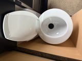 This RV rental's white portable toilet is shown with its lid open, revealing the clean bowl and black drain plug on a wood floor.