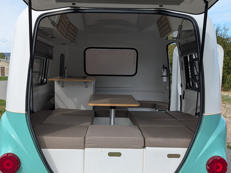  parked by a scenic lake with mountains in the background.|This vintage-style white and teal teardrop RV rental is ready for adventure in a scenic park — photo 3