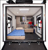 Spacious RV rental interior: A toy hauler's versatile living/garage area with bed, sofa, storage, and ramp. Perfect for adventures.